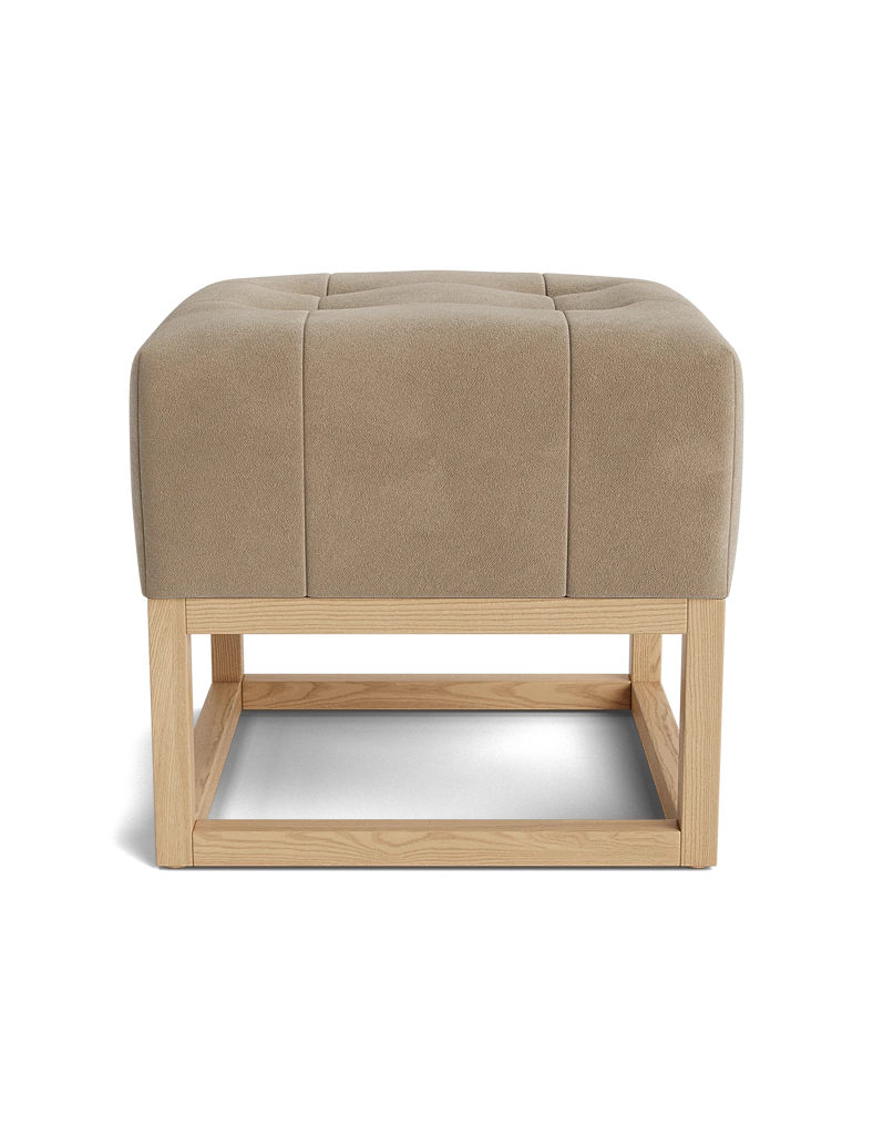 Side view of a latte-colored tufted velvet ottoman with a light wood base.